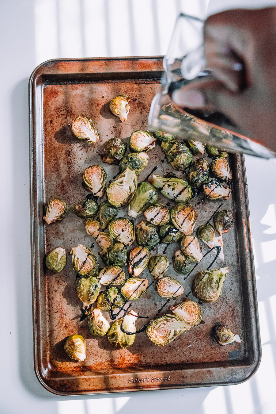 Roasting pan with Brussels Sprouts and balsamic glaze drizzled on top.