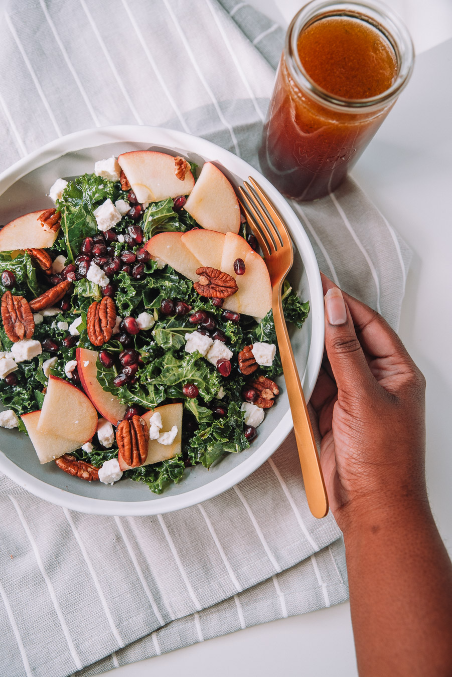 Kale Apple Salad with Pomegranate Dressing sprinkled with feta cheese crumbles and pecans in a bowl. 