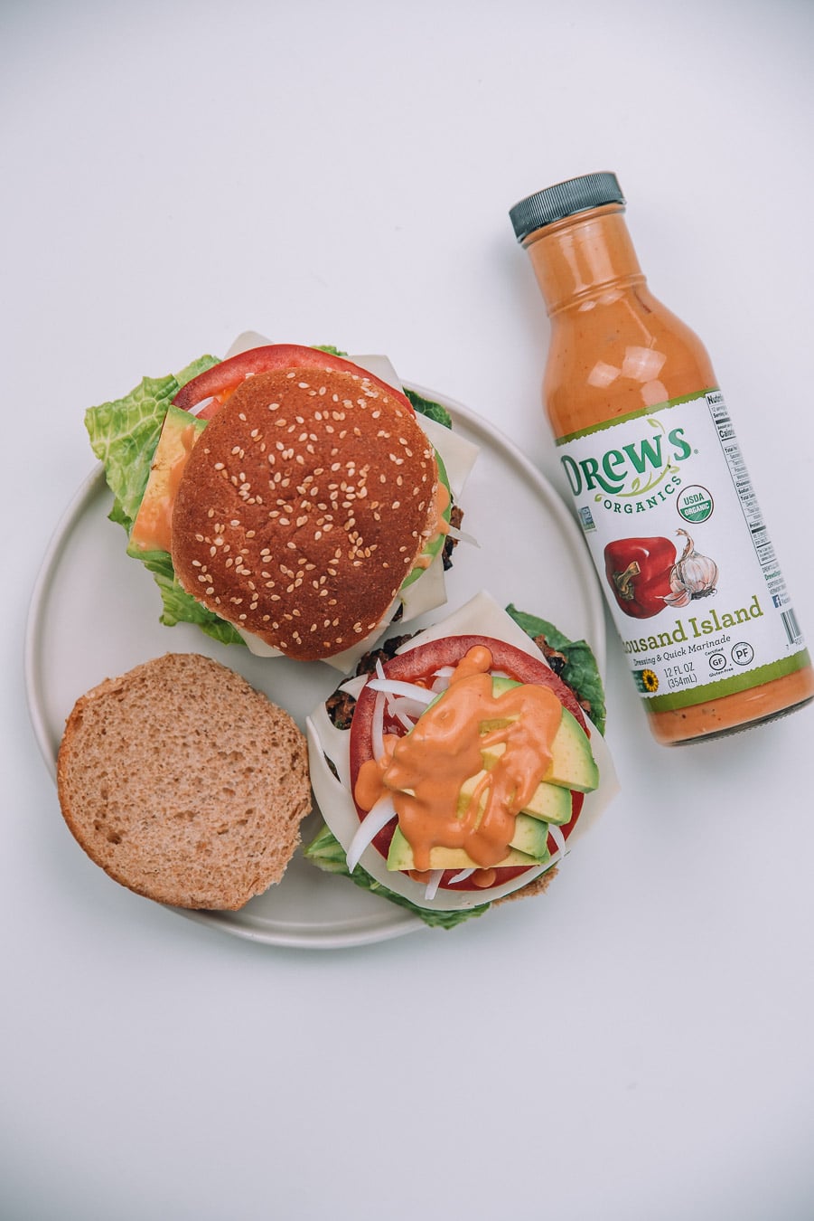 2 black bean burgers on a white plate with a bottle of Thousand Island Dressing