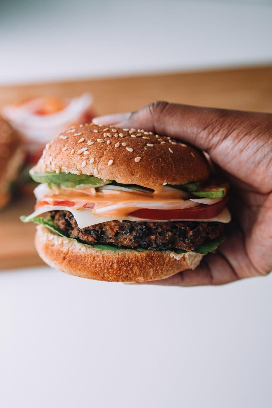 2 black bean burgers on a white plate with a bottle of Thousand Island Dressing