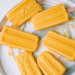 Melting mango lassi popsicles on a plate