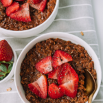 Thick of bowl of chocolate oatmeal with strawberries and chia seeds.