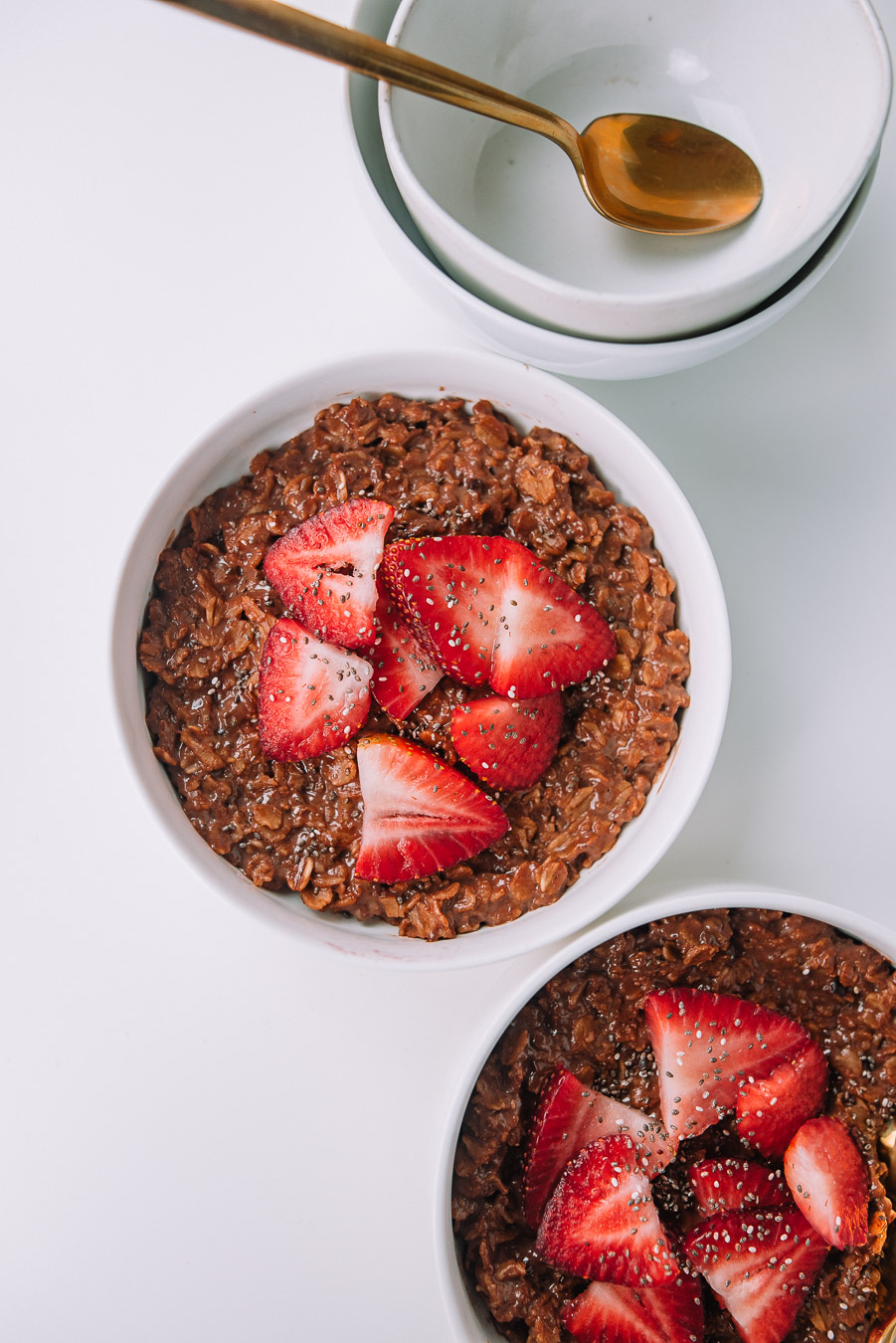 Thick of bowl of chocolate oatmeal with strawberries and chia seeds. 