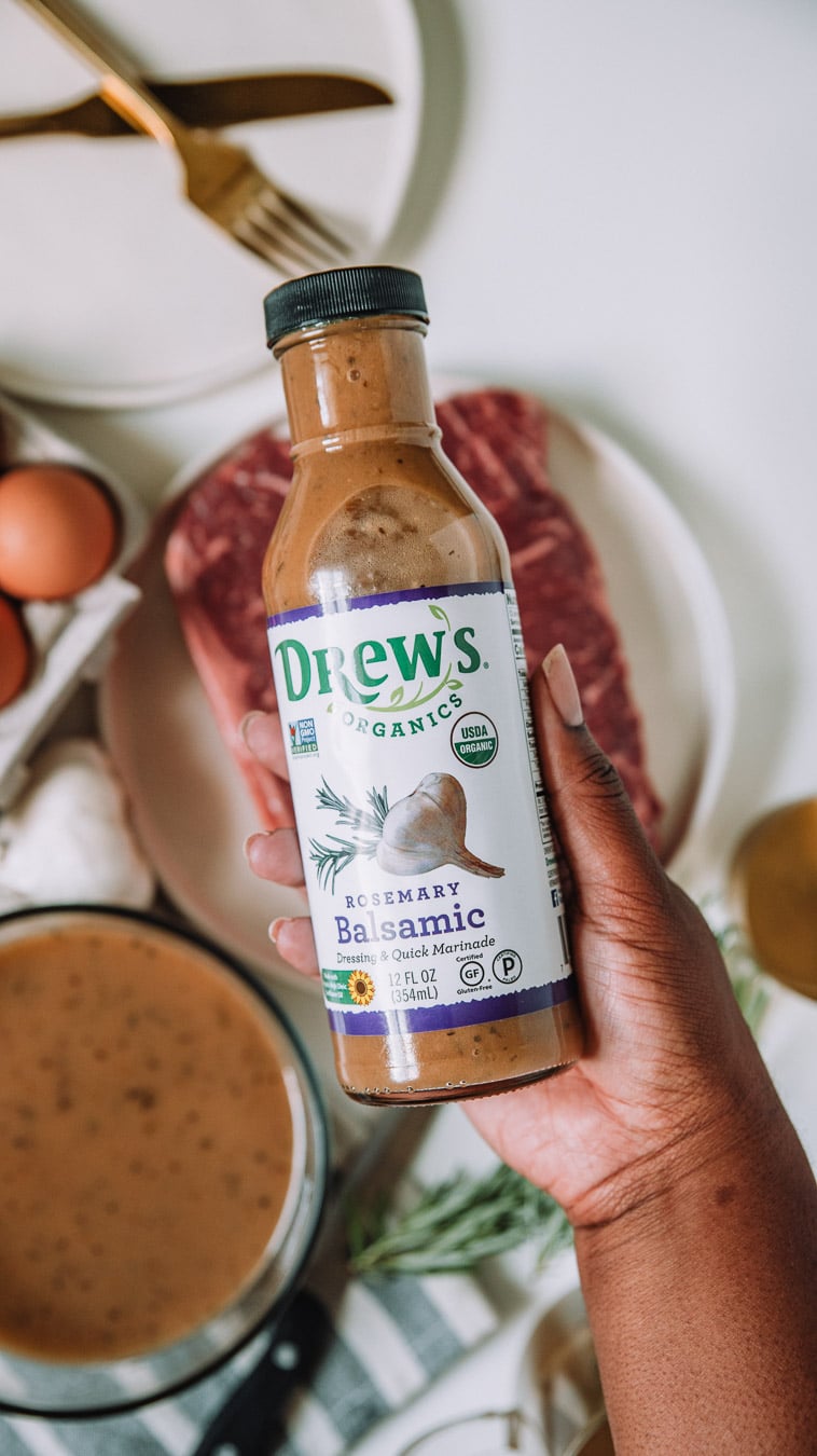 hand holding a bottle of Drew's Organics Rosemary Balsamic Quick Marinade and Dressing. 