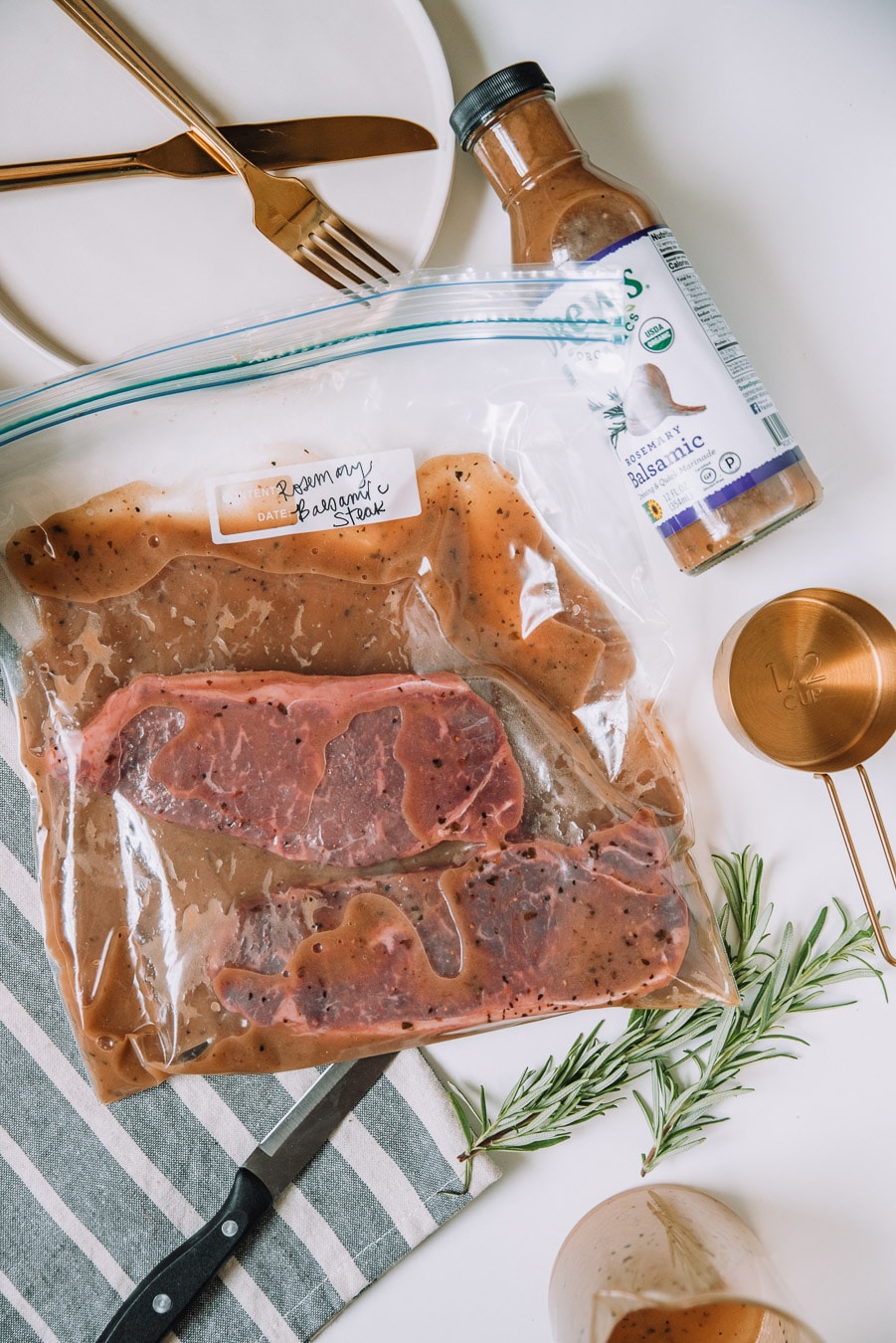 Steaks in a plastic bag marinating on a white table.