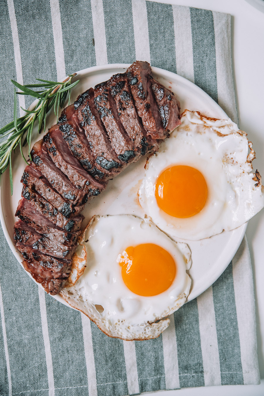 Rosemary steak and eggs on a white plate