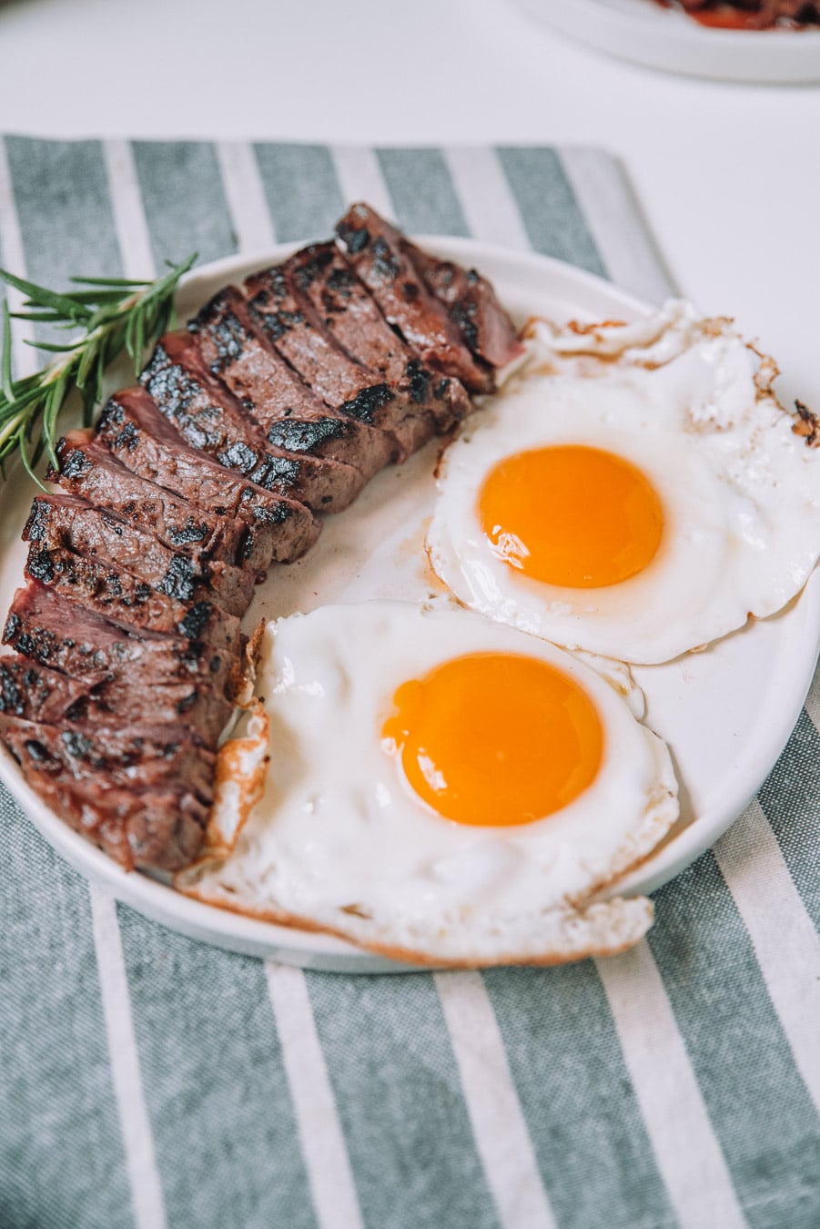 Rosemary Balsamic steak and Eggs on a white plate. 