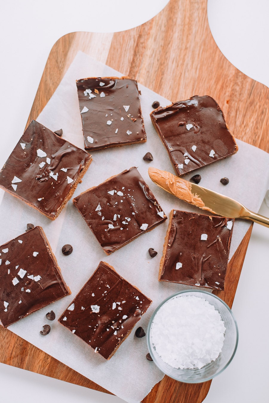 No bake peanut butter chocolate bars on white parchment paper and wood board. 