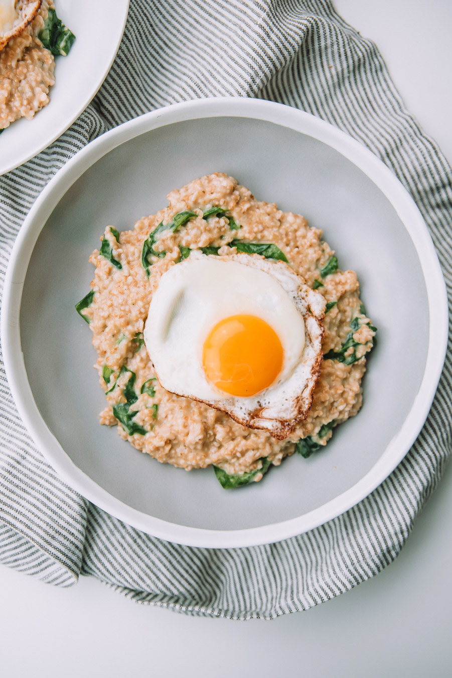 Bowl of savory spinach oatmeal with fried eggs