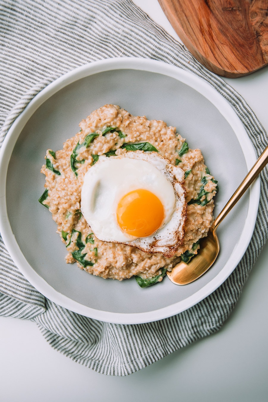 Bowl of savory spinach oatmeal with fried eggs