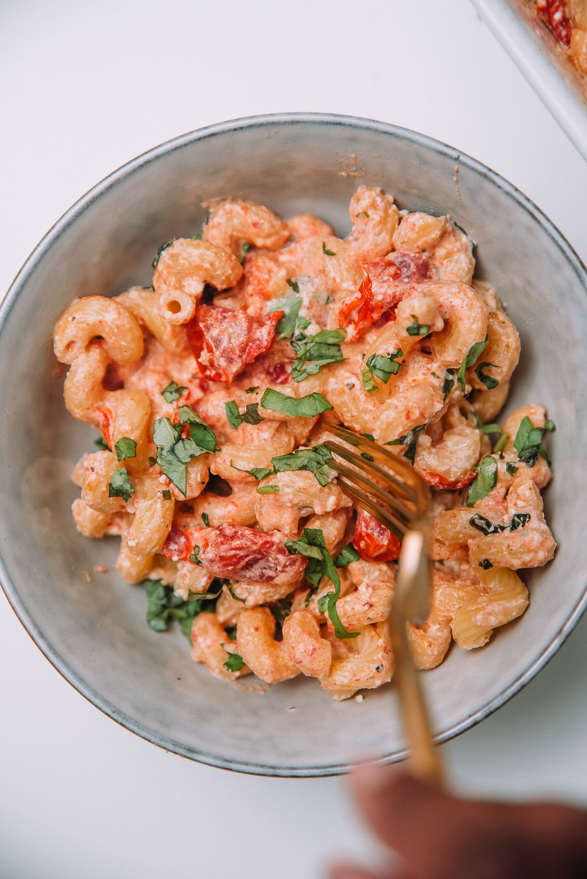 A grey bowl filled with Baked Feta Pasta with Cherry Tomatoes and g old fork. 