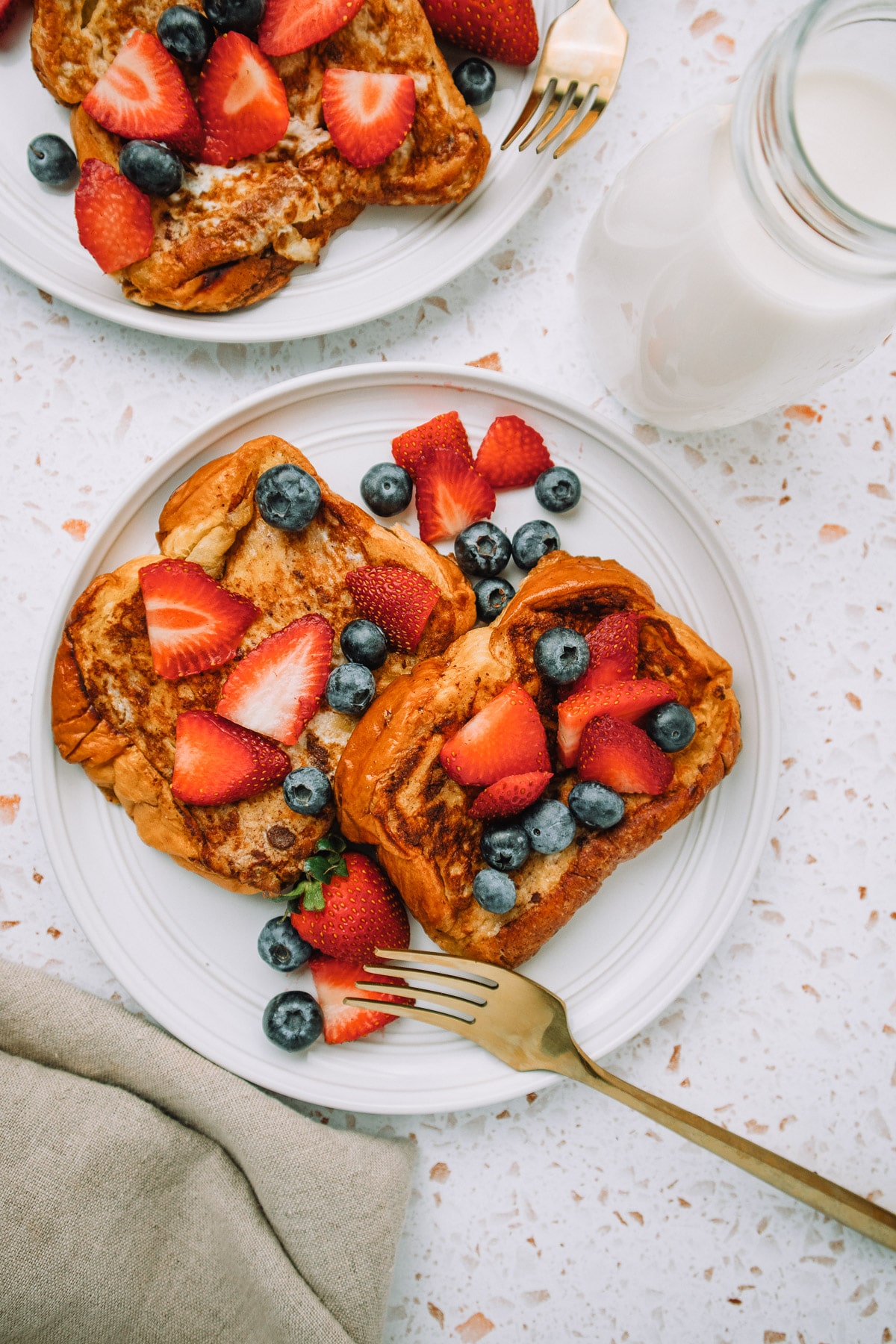 Delicious slices of brioche french toast stacked on a plate with fresh strawberries and blueberries for a yummy breakfast or brunch