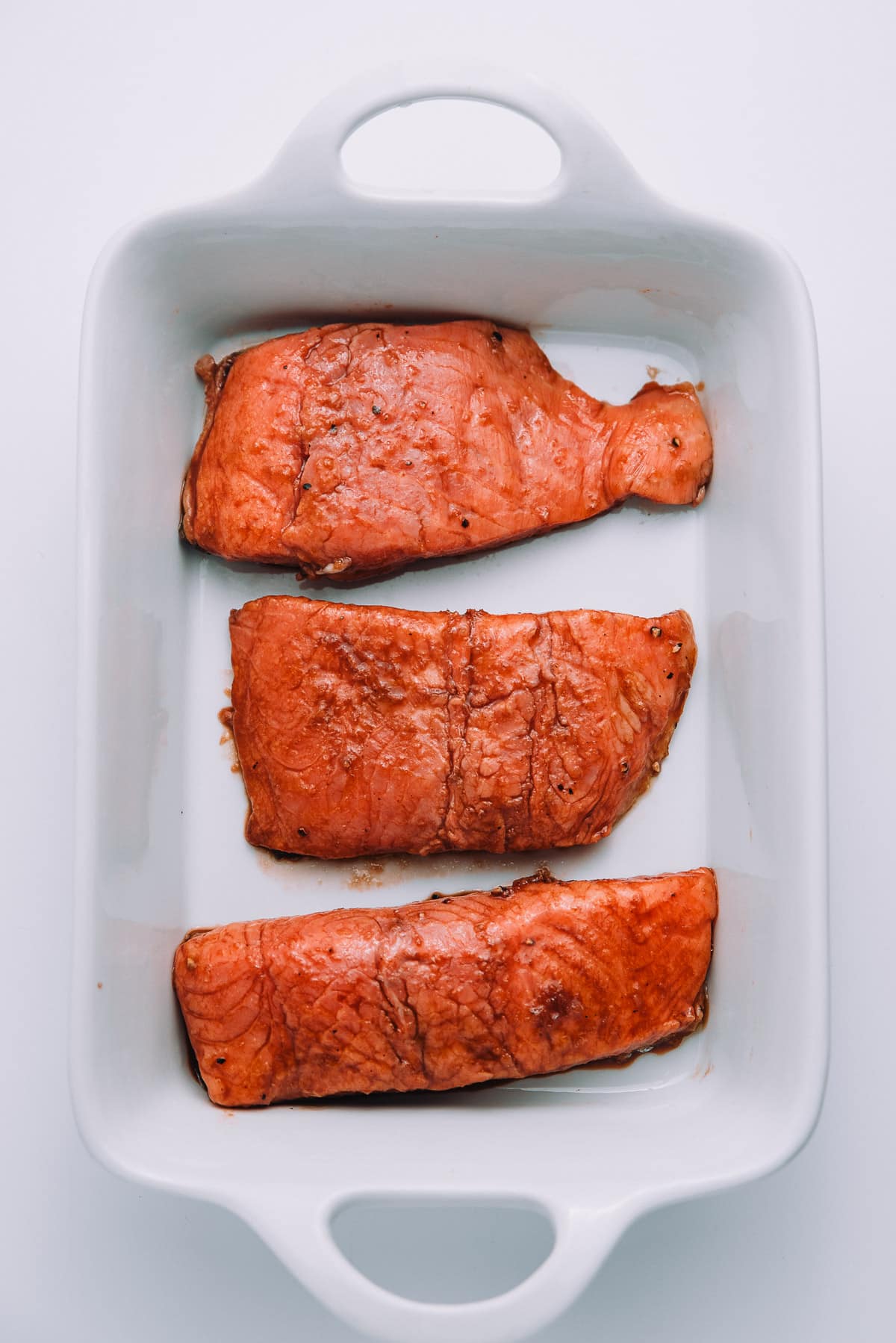 Marinated salmon in a baking dish. 