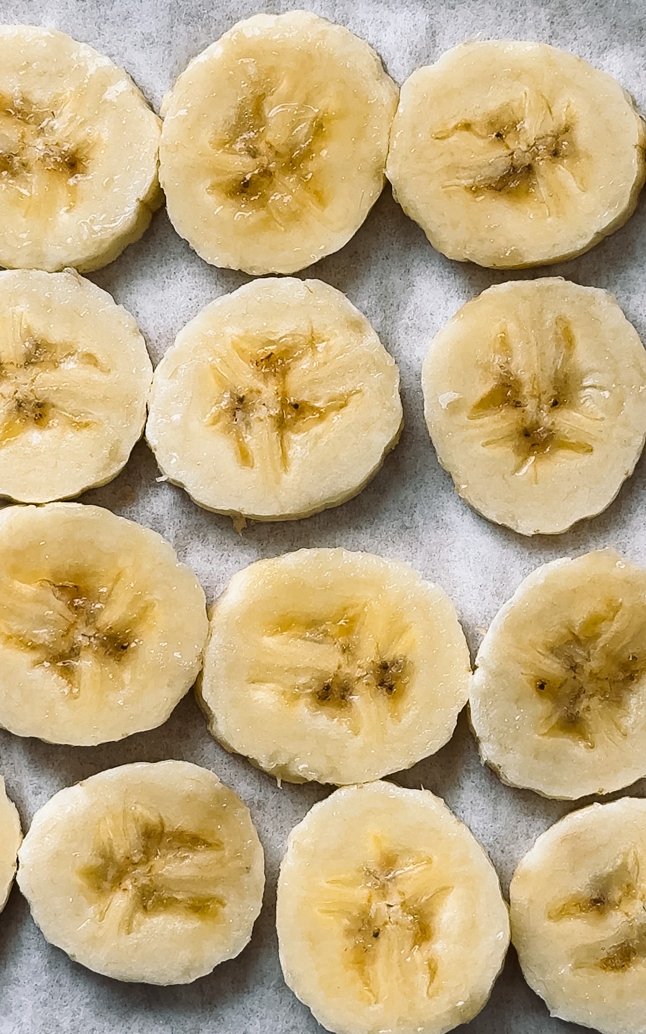 Fresh banana slices layed on parchment paper